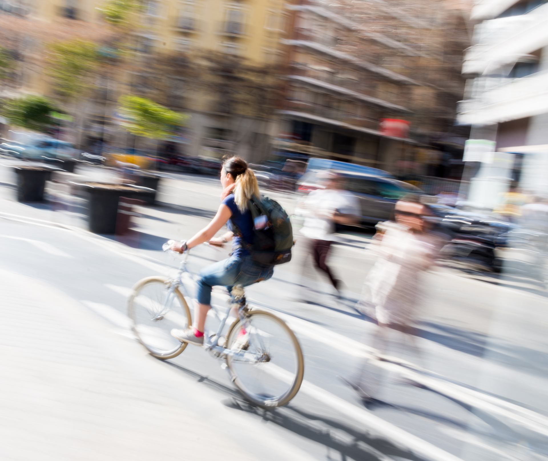 Eine Frau auf einem Fahrrad, die die Straße hinunterfährt. Bewusste Bewegungsunschärfe