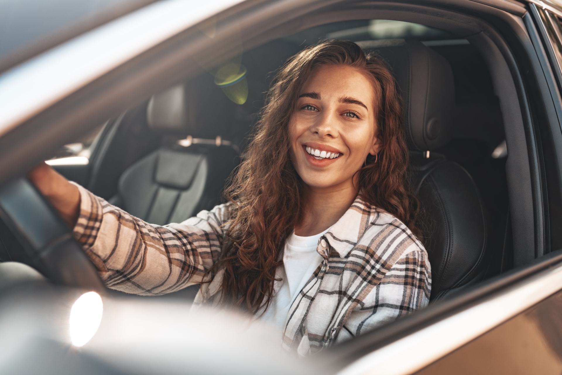 Porträt einer lächelnden Frau in einem Auto, die aus dem Fenster schaut