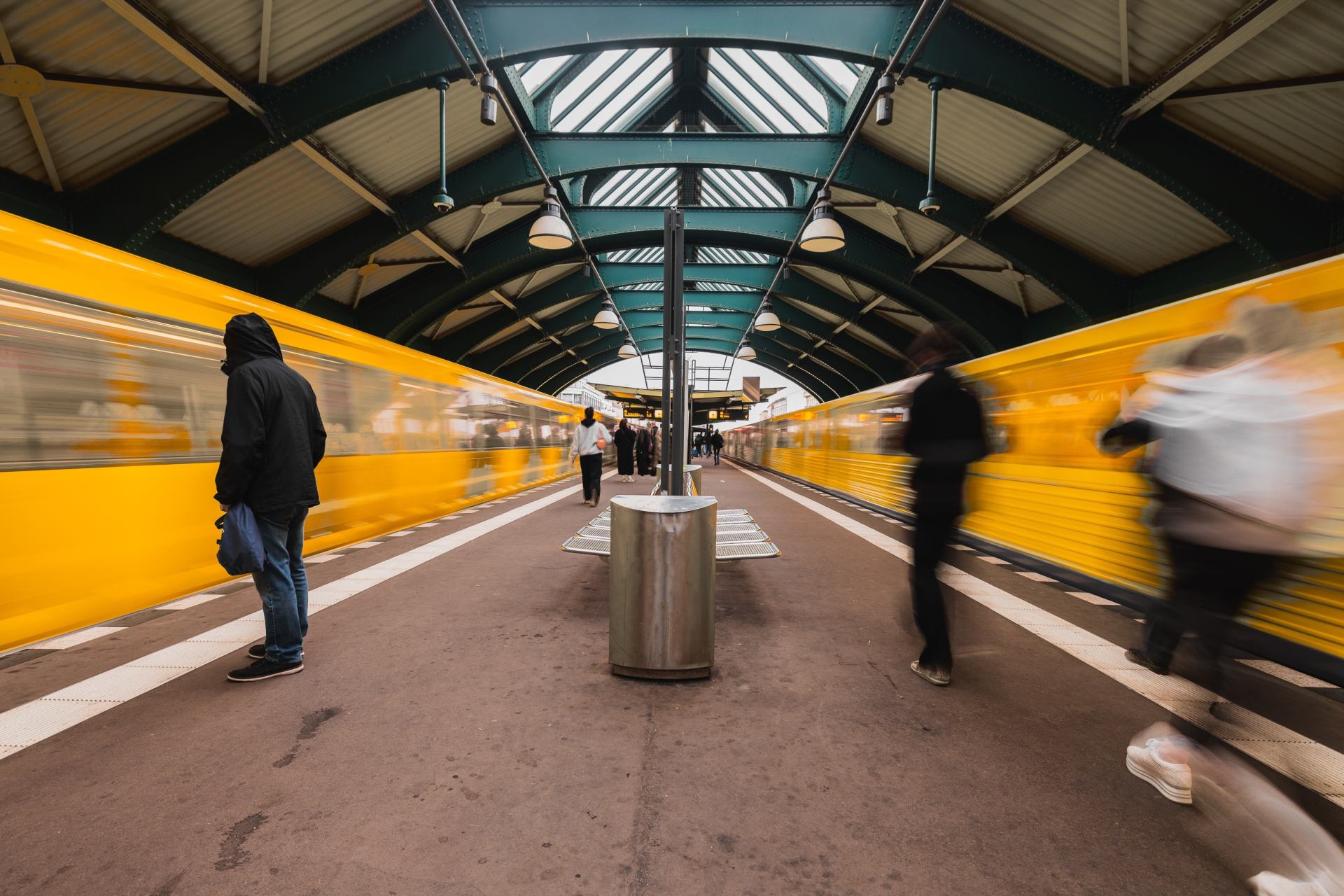 U-Bahn-Station, alter Bahnhof aus Metall. Zwei Züge, die gerade in Bewegungsunschärfe in den Bahnhof einfahren. Öffentlicher Nahverkehr, viele Menschen und effizienter Personentransport.