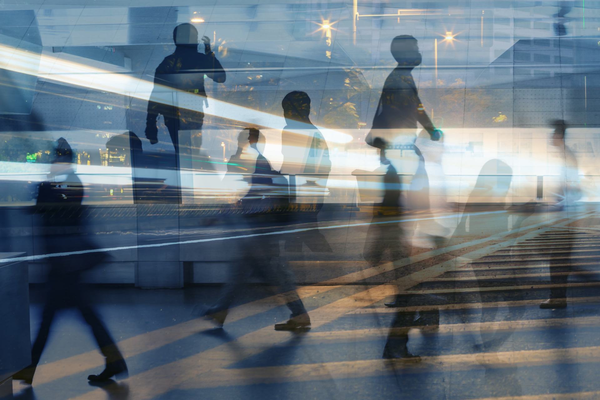 Geschäftsleute auf dem Weg zur Arbeit, die nachts durch die Stadt gehen, mit Bewegungsunschärfe und Lichtaufnahmen durch Doppelbelichtung